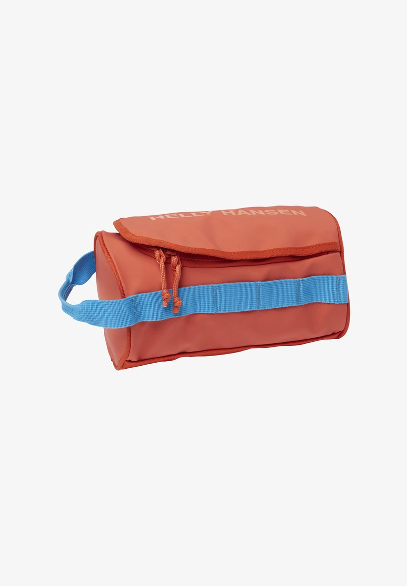 Bolsa impermeable roja con una correa azul. Cuenta con una solapa plegable y cordones laterales. Logo de "Helly Hansen" impreso en blanco. Forma rectangular.
