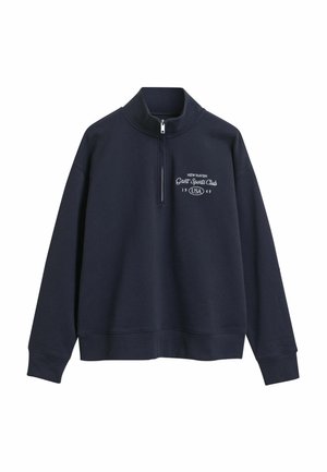 Navy blue pullover made from soft fabric, featuring a quarter zip, high collar, and white text logo detailing on the front.