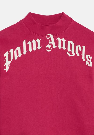 Gros plan d'un sweat-shirt rouge à col montant avec un texte gothique blanc ""palm Angels"" courbé sur la poitrine.