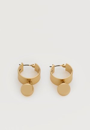 Paire de boucles d'oreilles créoles dorées avec des pendentifs circulaires plats suspendus à l’intérieur de chaque créole sur fond blanc.