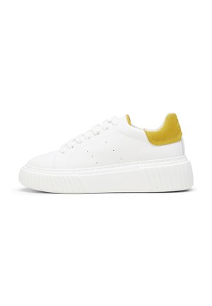 Baskets en cuir blanc avec une semelle en caoutchouc texturé, dotées d'un onglet de talon en daim jaune, de lacets ronds et de trous de ventilation sur les côtés.