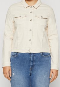 Hellcremefarbene Jeansjacke mit Druckkn öpfen, zwei Fronttaschen und einem Kragen. Verfügt über ein figurbetontes Design und eine leicht strukturierte Oberfläche.