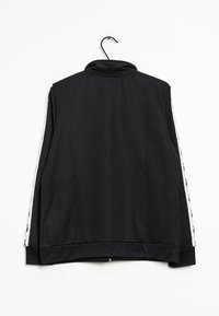 Czarna kurtka na zamek z wysokim kołnierzem, z białymi paskami po bokach i gładką, elastyczną tkaniną.