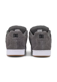 Harmaat mokkapinta sneakersit, joissa on teksturoitu pinta, valkoiset kumipohjat ja musta logo kantapäässä, sekä hengittävä verkkovuori.