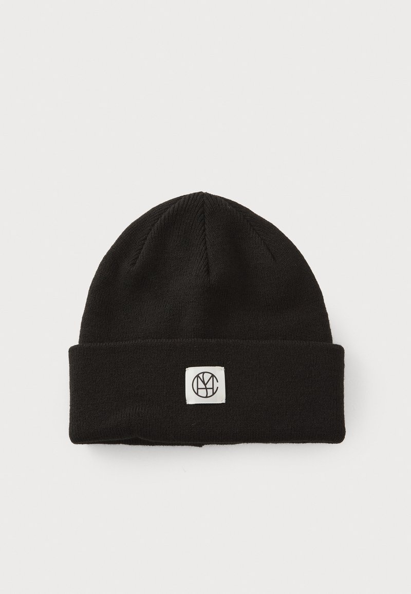 Un bonnet noir en tissu tricoté, avec un revers replié et une étiquette blanche rectangulaire avec un logo noir à l'avant.
