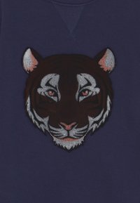 Felpa color navy con testa di tigre ricamata in tonalità di marrone, nero e bianco, con dettagli facciali e accenti rosa.