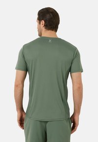 Zielona, krótkosleeve koszulka sportowa z teksturowanej tkaniny i okrągłym dekoltem. Logo nadrukowane na górnej części pleców. Zaprojektowana z myślą o aktywnym stylu życia.