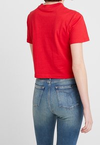 Rød bomulds cropped t-shirt med korte ærmer, parret med blå denim jeans med klassisk pasform og baglommer.