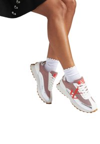 Baskets en mesh blanches et rouges avec des accents argentés, dotées d'une semelle épaisse et d'un système de laçage prononcé, accompagnées de chaussettes blanches à volants.