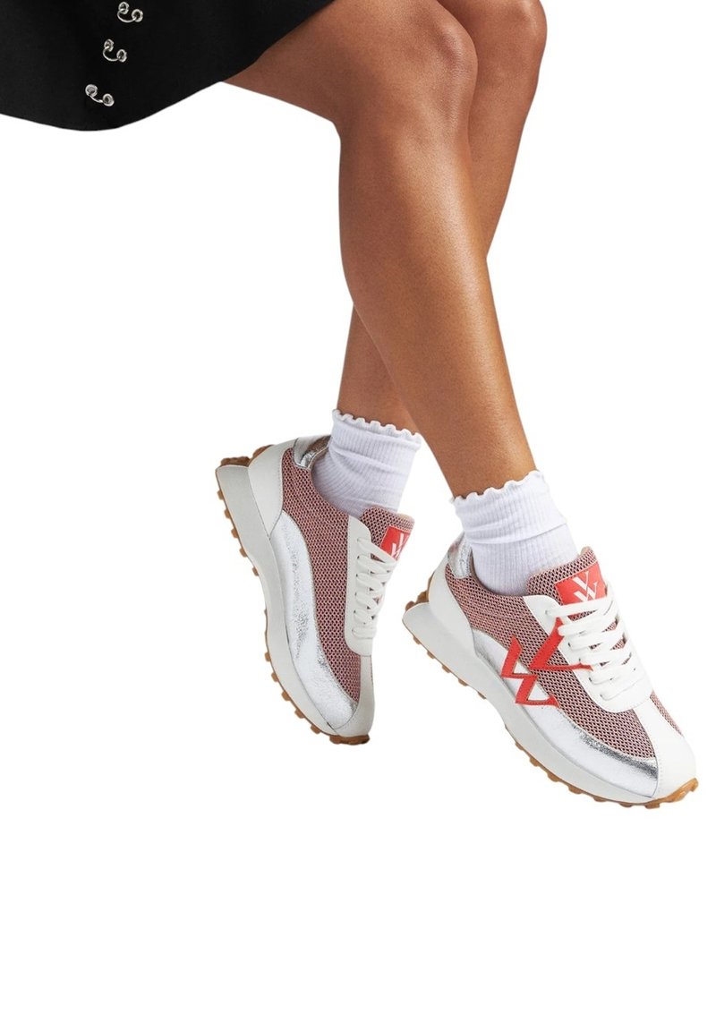 Baskets en mesh blanches et rouges avec des accents argentés, dotées d'une semelle épaisse et d'un système de laçage prononcé, accompagnées de chaussettes blanches à volants.