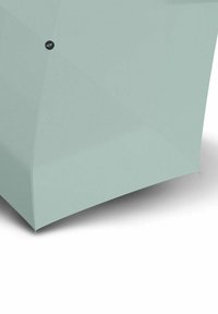 Lichtgroene paraplu met een gladde, matte buitenkant en een modern geometrisch ontwerp; heeft een cirkelvormig logo aan de ene kant.