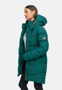Tealowa kurtka puchowa z kapturem, z teksturowanym wykończeniem, guzikami z przodu oraz naszywką na rękawie. Zaprojektowana z myślą o ciepłości i komforcie.