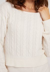 Weißer, kabelgestrickter Pullover mit weiter Ausschnittform und geripptem Saum. Verfügt über ein strukturiertes Muster und ein weiches, gemütliches Material.