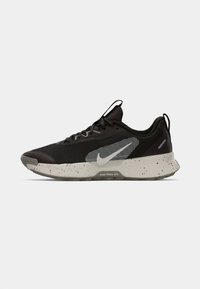 Nike trailrun-schoenen met een zwarte mesh bovenkant, grijze accenten, gespetterde tussenzool en rubberen buitenzool. Vetersluiting met een trekhaak aan de hiel.