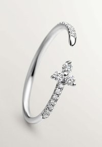 Anillo de tono plateado con una banda lisa, que presenta piedras redondas transparentes y un delicado diseño de mariposa adornado con piedras adicionales.