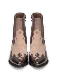 Stivali alla caviglia marroni e beige con una tomaia in suede, ritagli decorativi e una punta lucida e testurizzata. Chiusura con cerniera sul retro. Suola piatta.