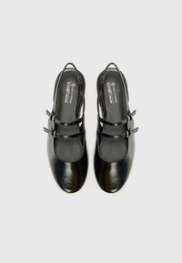 Black vegan leather shoes with a rounded toe, adjustable double straps, smooth texture, and a sleek design from the top view.