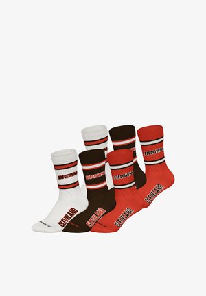 Zestaw skarpet w kolorach białym, brązowym i pomarańczowym z prążkowanymi ściągaczami. Na nich znajdują się napisy "BROWNS" i "CLEVELAND", podkreślone poziomymi paskami.