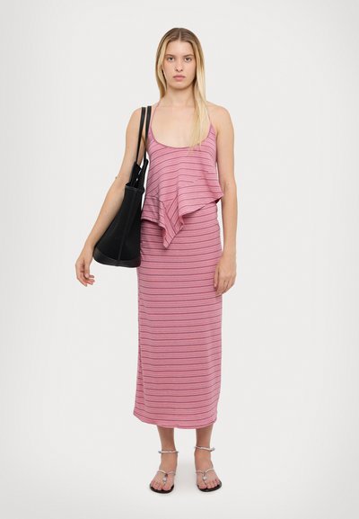Robe sans manches à rayures roses avec un design à volants, longueur cheville, associée à un sac fourre-tout noir et des sandales à lanières argentées.
