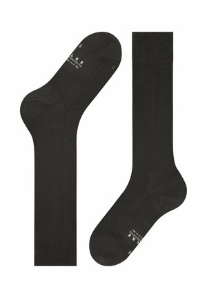 Paire de chaussettes noires montantes jusqu'aux genoux, avec des bords côtelés et un texte de marque subtil près des orteils et des chevilles.