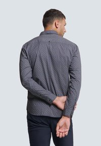 Lange mouwen, knoopsluiting overhemd in donkerblauw met een geometrisch patroon. Heeft een kraag en knoopmanchetten, en toont een gestructureerde stof.