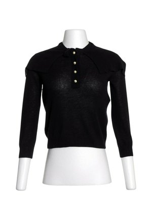 Top de punto negro de manga larga con tapeta frontal de botones que presenta cuatro botones tipo perla en un torso de maniquí blanco.