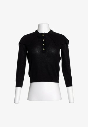 Top de punto negro de manga larga con tapeta frontal de botones que presenta cuatro botones tipo perla en un torso de maniquí blanco.