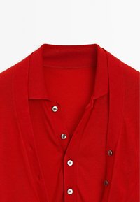 Röd cardigan med krage, prydd med sex silverknappar fram. Tillverkad av ett mjukt, stickat material med en jämn textur.