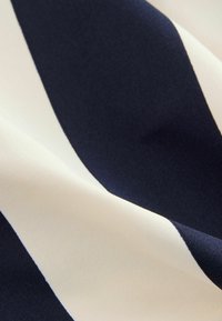 Tkanina bawełniana z szerokimi granatowo-niebieskimi i kremowymi paskami, gładka w dotyku, z lekko błyszczącym wykończeniem, prezentująca prosty, odważny wzór.