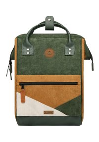 Zaino in corduroy verde, marrone e crema con una tasca frontale con zip, maniglie superiori e una patch rotonda con logo. Dettagli in tessuto testurizzato.