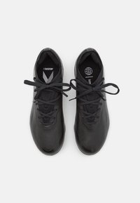 Schwarze Sportschuhe mit strukturierter Oberfläche, runder Zehenpartie und flachen Schnürsenkeln. Sie verfügen über eine gepolsterte Innensohle und ein Branding auf der Lasche.