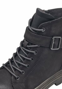 Bottes de cheville en cuir noir avec des lacets gris, un détail de sangle à boucle et une surface texturée. Bout rond et semelle basse et solide.