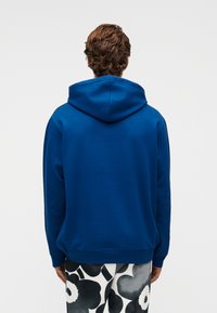 Μπλε φούτερ με κουκούλα και λεία υφή, με κορδόνι στην κουκούλα και ριμπ μανσέτες, συνδυασμένο με παντελόνι με σχέδια.