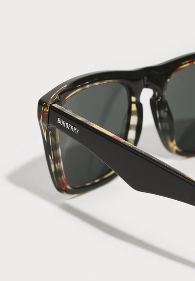 Okulary przeciwsłoneczne Burberry z czarną plastikową oprawą, ciemnymi soczewkami i wzorem w kolorze żółwia na przodzie. Logo na zauszniku w białym kolorze.