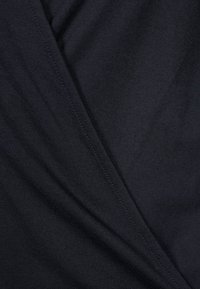 Svart tyg med en slät textur, med en diagonalt veck eller drape och synlig söm längs kanterna.