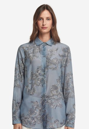 Helles blaues, transparentes Blusenoberteil mit kunstvollen silbernen Stickereien, langen Ärmeln und einem Kragen. Verfügt über florale und Paisleymuster.