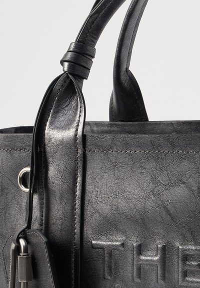 Zwarte leren handtas met een gestructureerd oppervlak, reliëfletters en gladde handgrepen; beschikt over een accent van zilverkleurige hardware en stikseldetails.