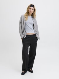 Grå t-skjorte under en svart og hvit rutete oversized skjorte, supplert med svarte joggebukser og svarte leiligheter, med en avslappet passform.