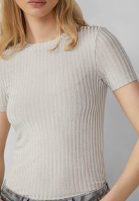  Lichtgrijze geribbelde t-shirt met korte mouwen, met een ronde hals en een aansluitende pasvorm. De stof heeft een subtiele glans.
