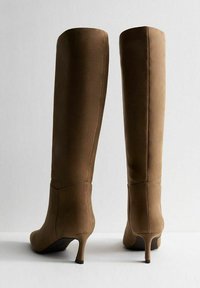 Stivali over-the-knee in suede marrone con punta affusolata e tacco alto e sottile. Texture liscia e design pulito e minimalista.