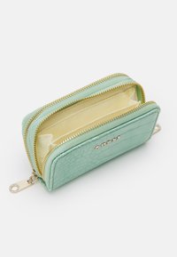 Portefeuille vert menthe avec un extérieur en cuir texturé, fermeture éclair dorée et deux compartiments doublés de tissu jaune. Présente des clous décoratifs.