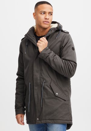 Dark grey parka jacket with a fur-lined hood, adjustable drawstrings, side pockets, and silver hardware accents. Cotton blend fabric.