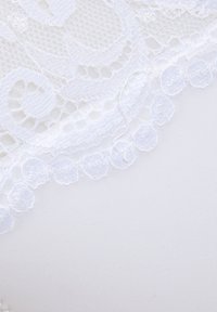 Weißes Spitzengewebe mit kunstvollen Blumenmustern und zarten gewellten Kanten, vor einem glatten weißen Hintergrund.