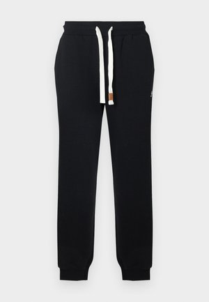 Zwarte katoenen joggers met elastische tailleband, wit aantrekkoord en subtiel logodetail. Toegelopende enkels met geribbelde boorden. Gladde textuur.