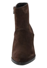 Botín de ante marrón hasta el tobillo con forma acampanada, textura suave y suela de goma negra. Cuenta con un cierre lateral para facilitar su uso.