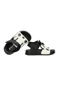 Sandales pour enfants noires et blanches avec motif visage de panda sur la bride avant et fermeture velcro sur fond blanc.