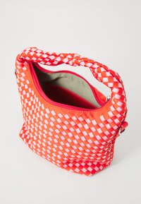Borsa intrecciata rossa e rosa con manico intrecciato, chiusura a zip e interno foderato con tasca. Superficie testurizzata con motivo a scacchi.