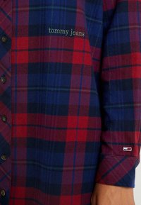 Rutig skjorta i röd och blå, med knappstängning, i bomull, med "Tommy Jeans" broderat i grönt, liten logotypdetalj på ärmen.