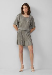 Grijze plissé tweedelige set met korte mouwen en shorts. Gladde, glanzende textuur met verticale strepen. Open halslijn, relaxte pasvorm.