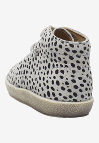 Botines de ante beige con lunares negros, punta redonda, bajo perfil y suela texturizada. Costuras decorativas y detalle del logotipo en el lateral.